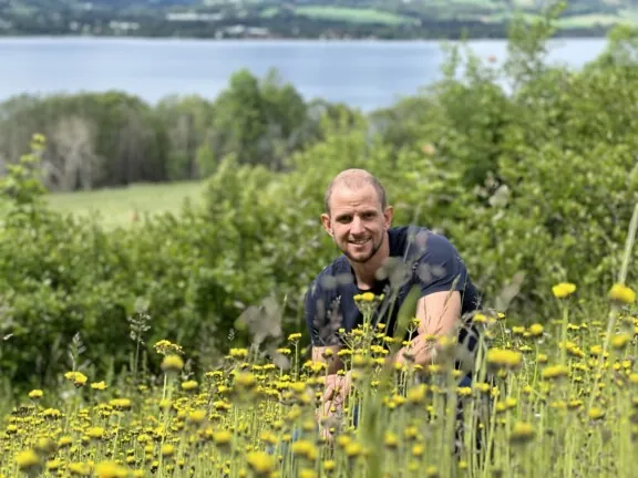 Ung mann i blomstereng, med Mjøsa i bakgrunnen