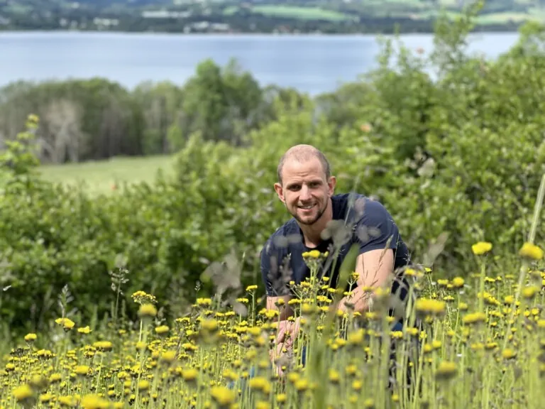 Ung mann i blomstereng, med Mjøsa i bakgrunnen